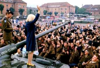 Sylvie Vartan debout sur un char saluant en 1964 une foule d'appelés du contingent